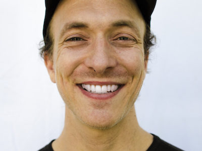Peter McCoy smiling in a black shirt against a white background